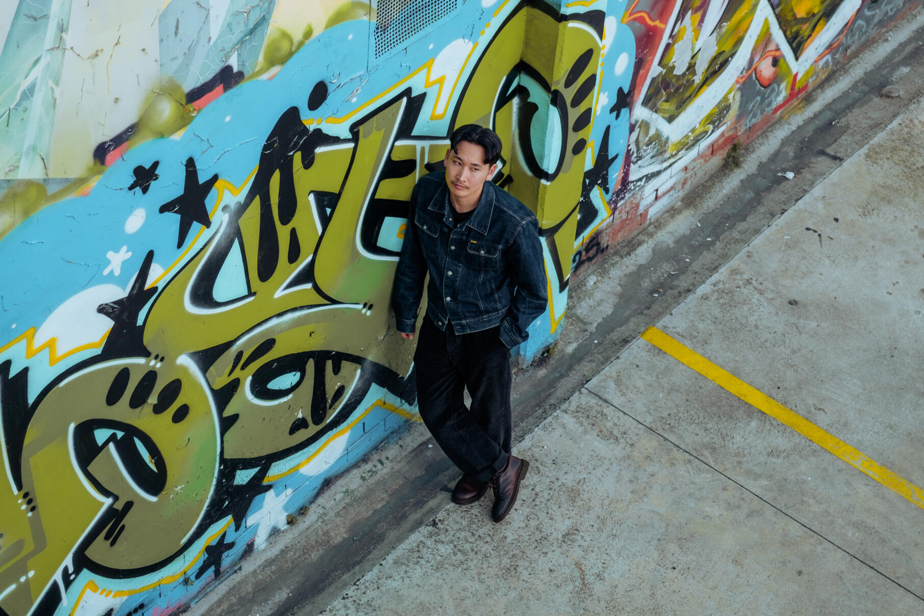 Man standing in car park, graffiti on wall
