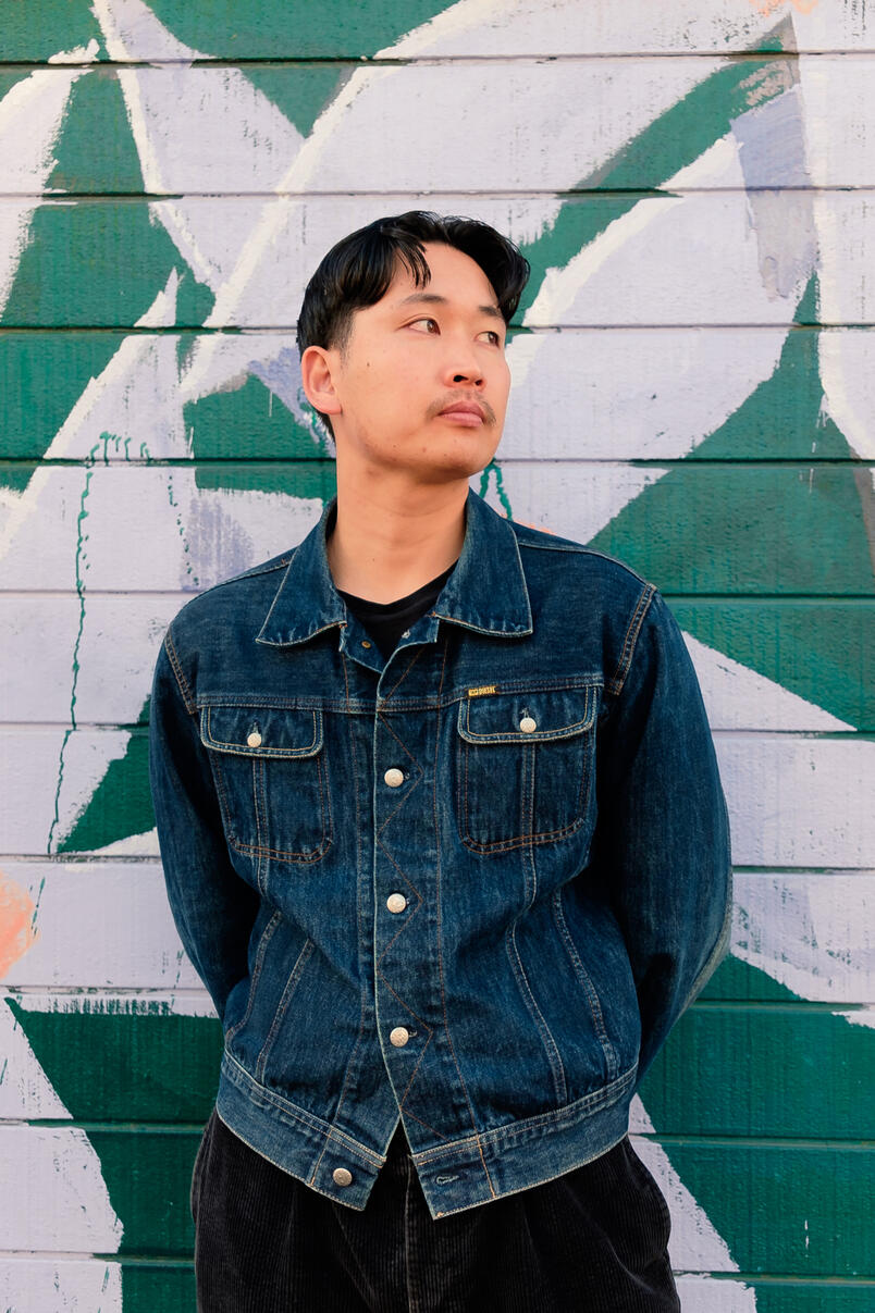 Man standing in front of green brick wall with painted flowers
