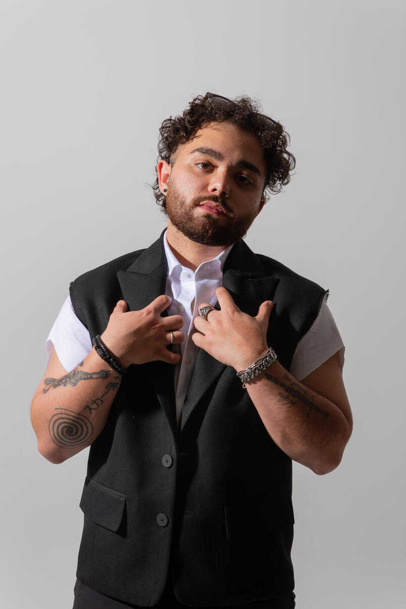 Studio image of a man adjusting the collar of his vest